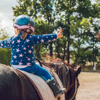 girl on a brown horse with her arms out to the side