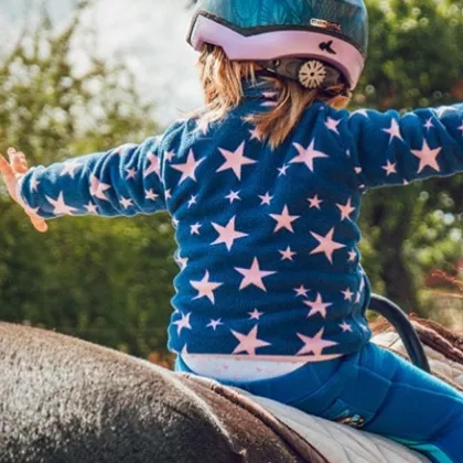 kid on a horse with their arms out. 