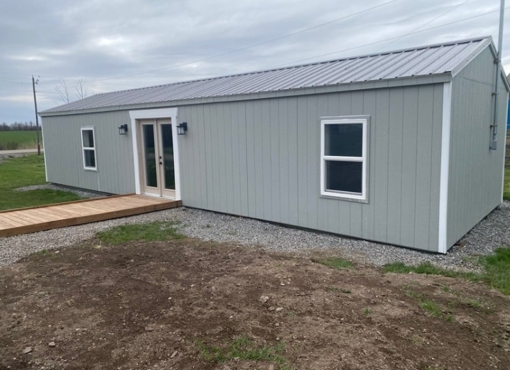 A side view of our blue-grey clubhouse, with a wooden ramp leading to the entrance.