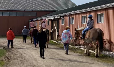 A group of riders walking around the barn. 