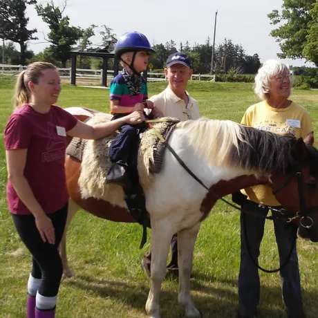 A little rider mounted outside on Wrangler, with 3 volunteers assisting him as his leader and side walkers. 