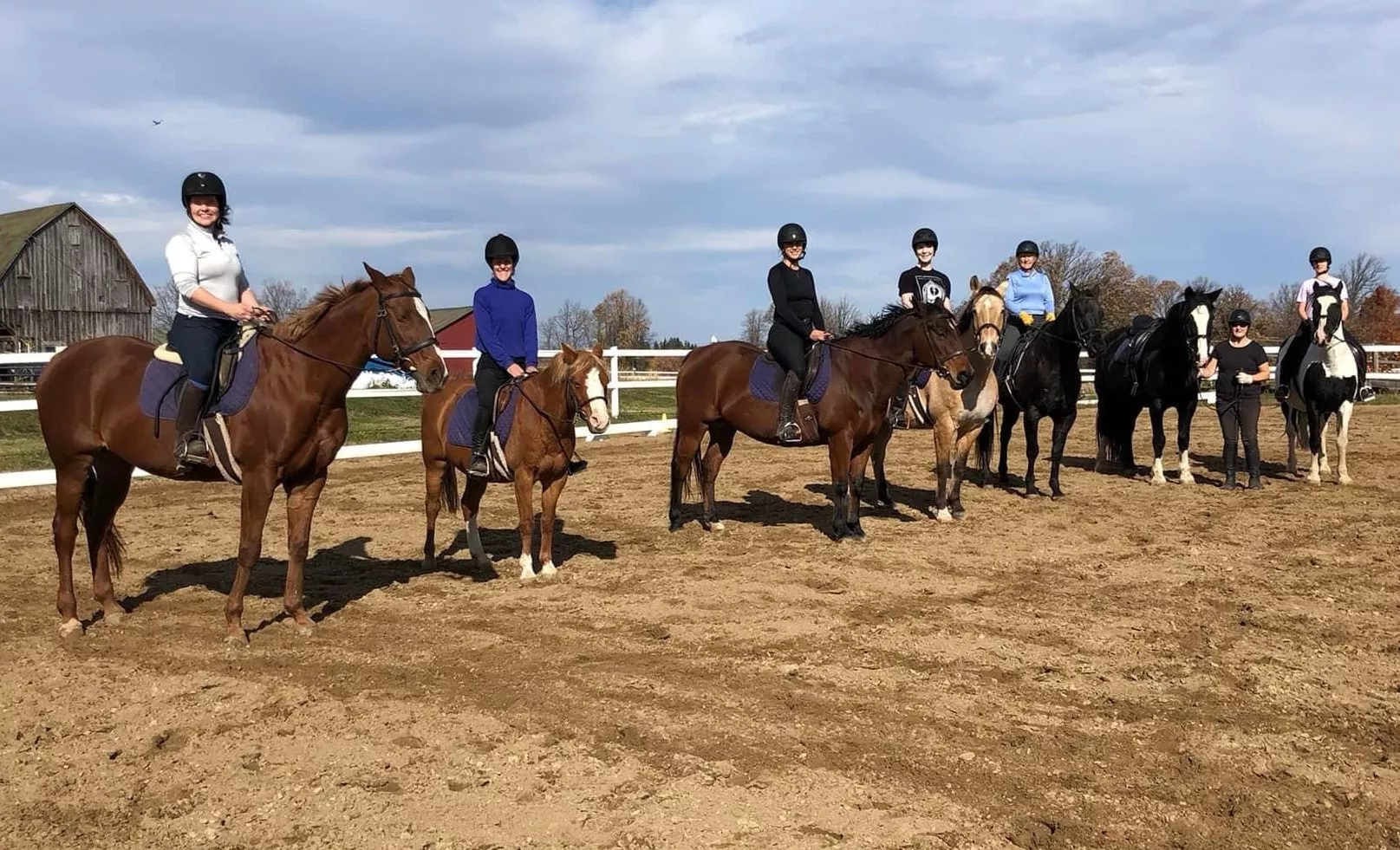 Some mounted staff members in the outdoor sand ring.