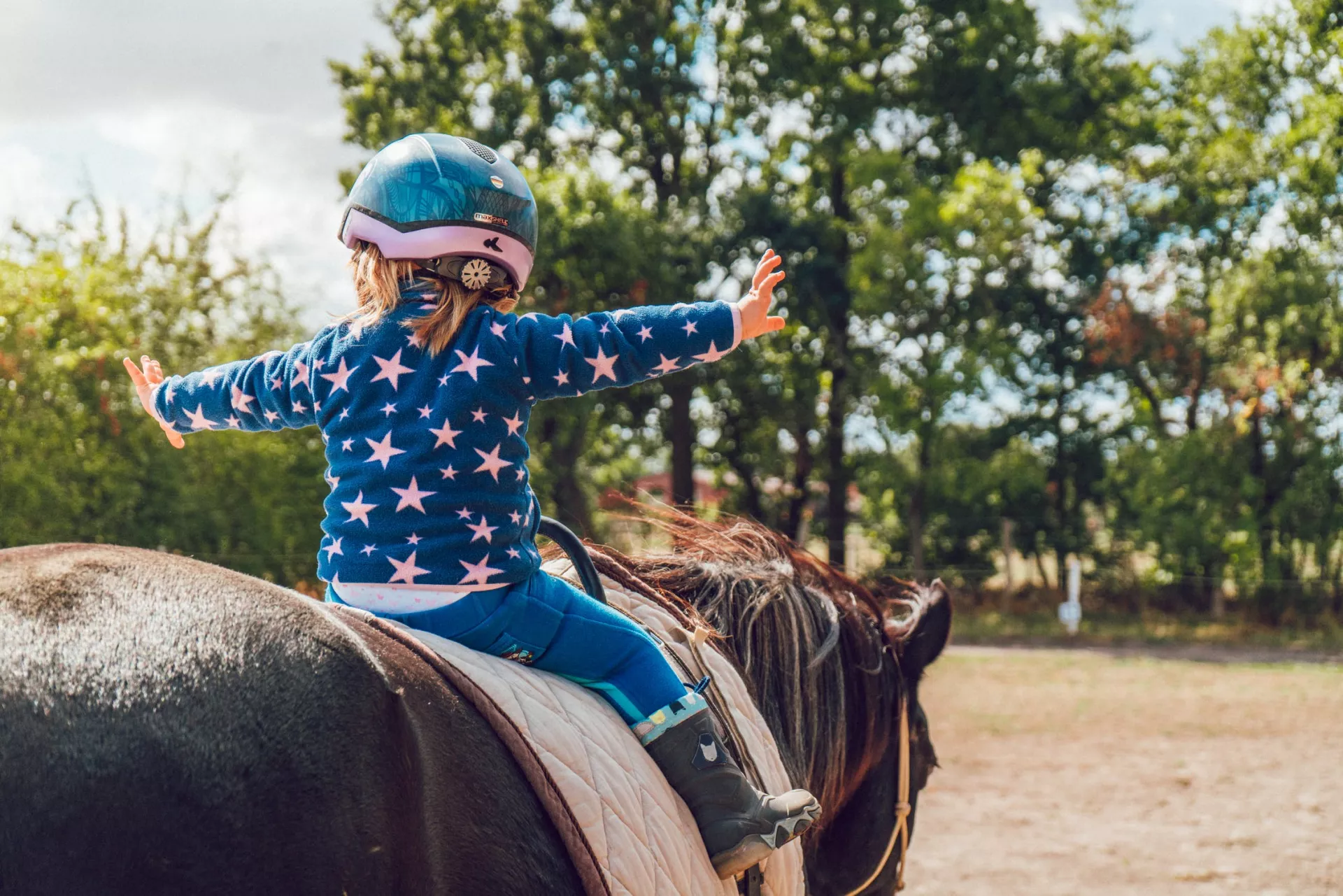 girl on a brown horse with her arms out to the side