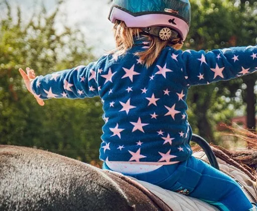 kid on a horse with their arms out. 